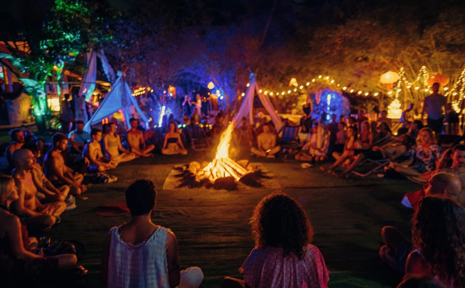 The AUM fire circle glowing under fairy lights at an evening ceremony